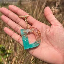 Blue and gold epoxy resin letter keychain with gold flakes and glossy finish.