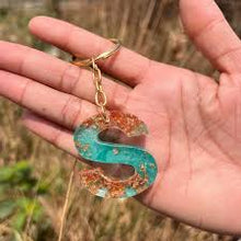 Resin letter keychain with blue shimmer and copper-colored flakes.