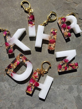 Floral resin letter keychains with gold accents in two colours.