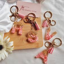 Pink and gold resin initial keychain with tassel and personalized letter.